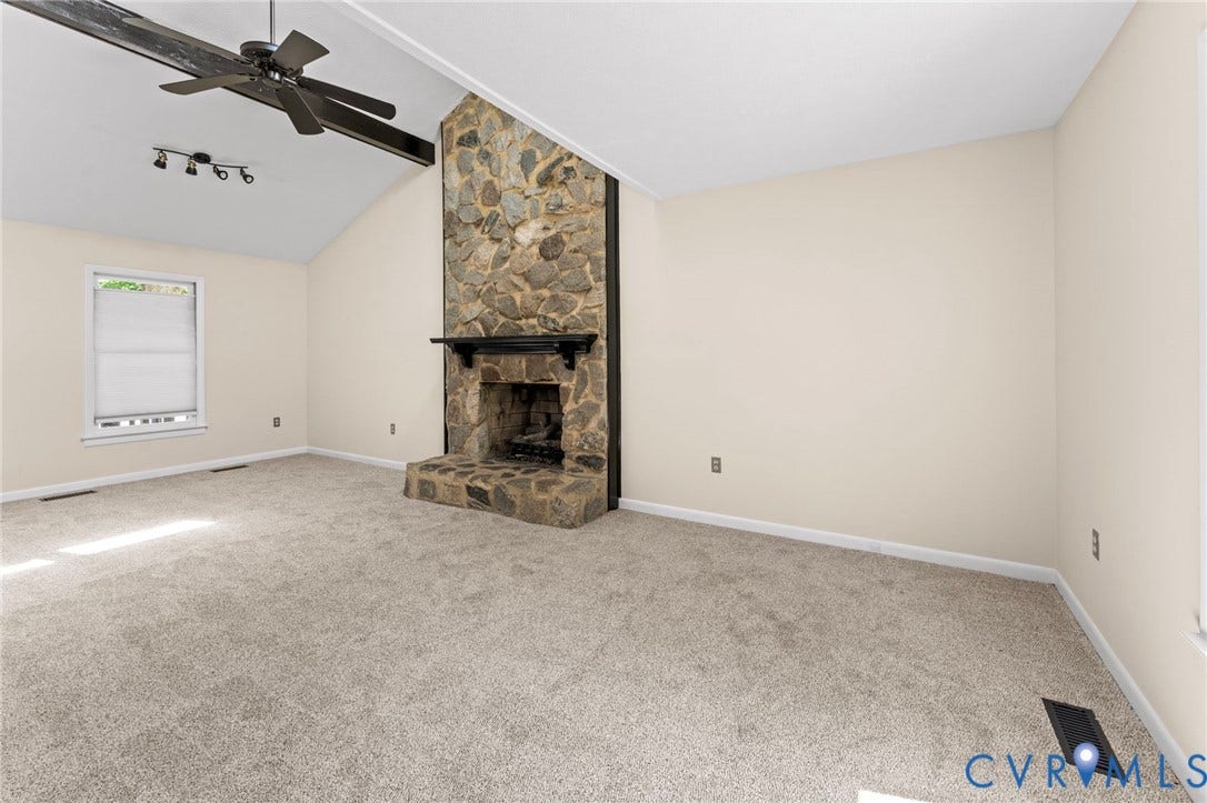 3020 Sand Hills Drive, Chester, VA 23831 Living area featuring a stone-clad fireplace and mantel, vaulted ceiling with exposed beam, and a ceiling fan