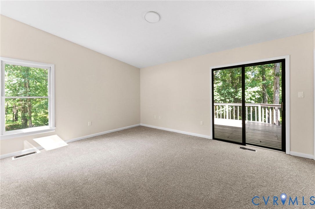 3020 Sand Hills Drive, Chester, VA 23831 Spacious room featuring neutral paint, wall-to-wall carpeting, a large window, and a sliding glass door opening to an exterior deck with white railings