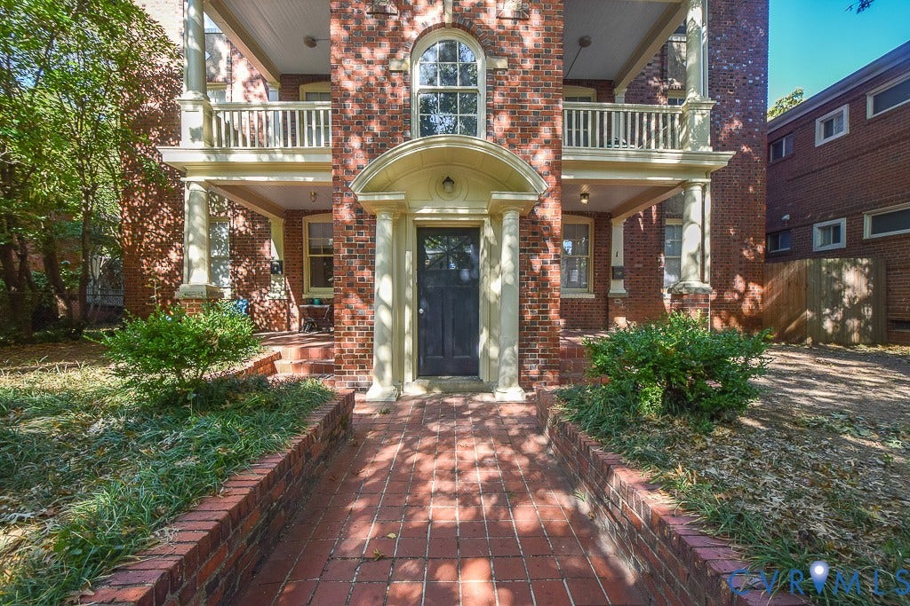 120 S Arthur Ashe Boulevard, #1, Richmond, VA 23220 Brick facade featuring a recessed entry with an arched pediment, a dark entry door, and a brick paver walkway