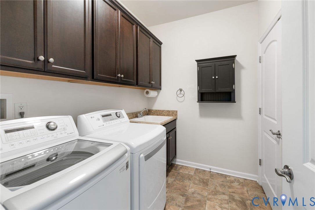 12128 Magnolia Bluff Court, Villas At Magnolia Lakes, Chester, VA 23831 Utility room featuring extensive dark wood cabinetry, a built-in sink with a stone-finish countertop, and durable flooring