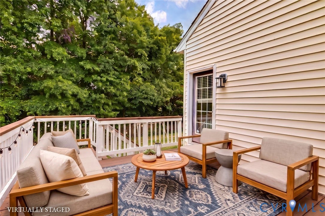 2244 Thomas Kenney Drive, Henrico, VA 23060 Exterior deck featuring white railings with wood-tone top rails, a light-colored siding wall, and a rear entrance door with an exterior light fixture. Virtually Staged