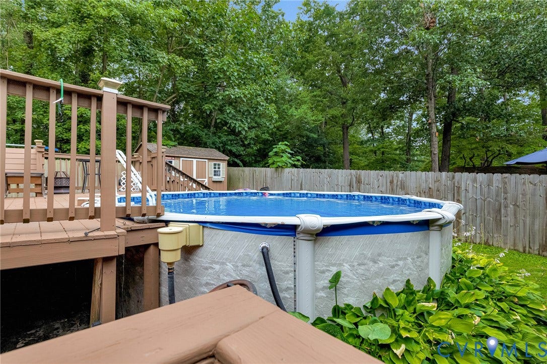 11330 Great Branch Drive, Chester, VA 23831 Expansive backyard featuring an above-ground pool, a wooden deck, a privacy fence, and mature trees
