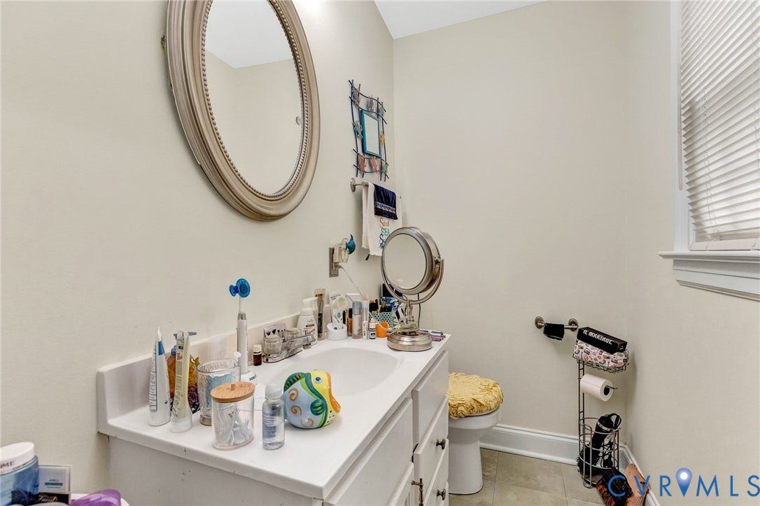 11330 Great Branch Drive, Chester, VA 23831 Bathroom vanity with an integrated sink, a large oval mirror, and a window with horizontal blinds