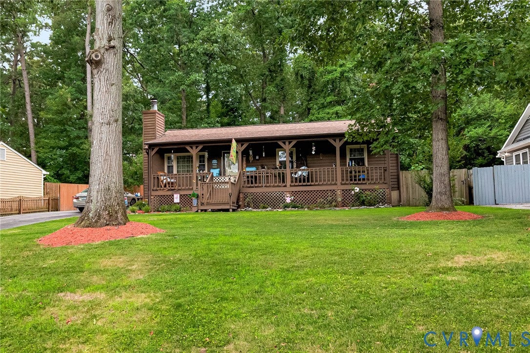 11330 Great Branch Drive, Chester, VA 23831 Brown wood-sided residence featuring a covered front porch with a lattice railing and a stone-clad chimney