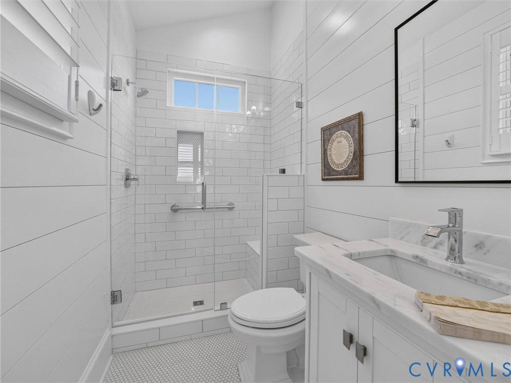Three-quarter glass shower enclosure with subway tile surround and integrated bench