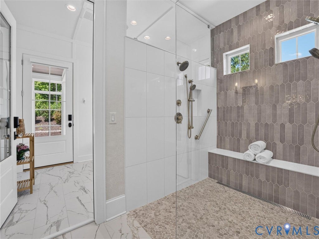 Shower with glass enclosure, pebble-finish flooring, and a built-in bench