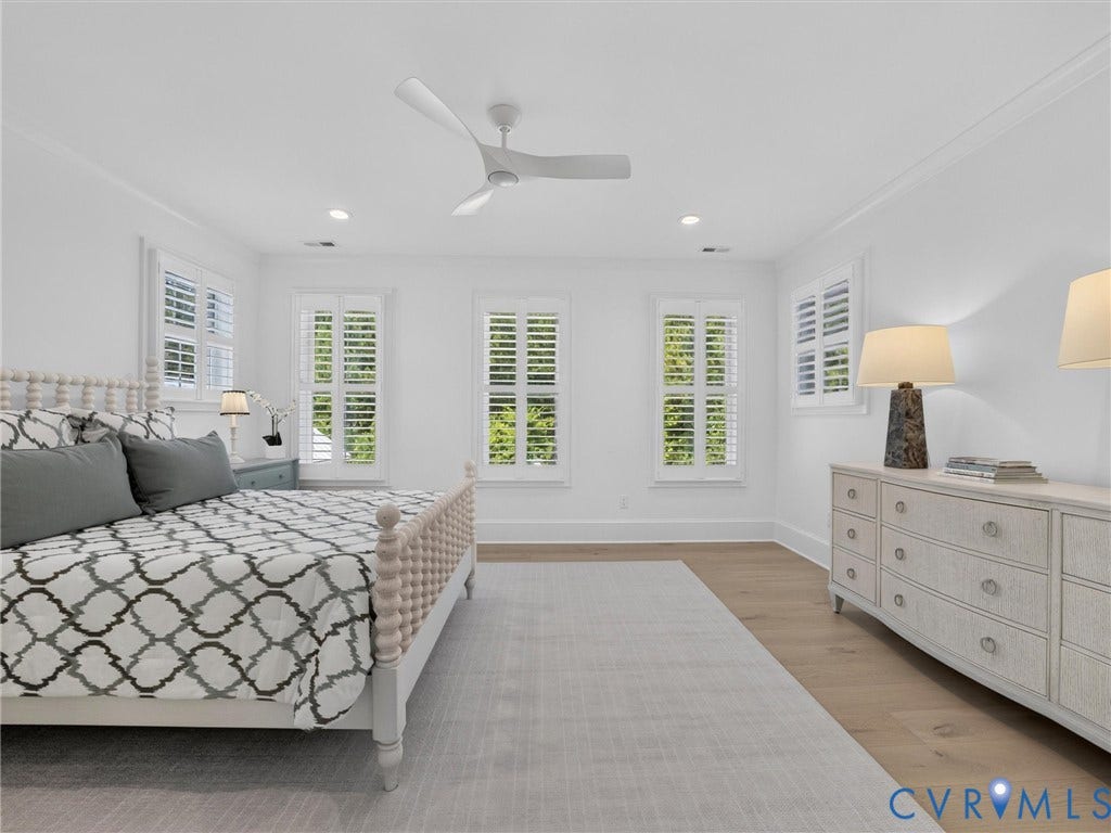 Bright room featuring multiple windows with white plantation shutters, crown molding, a ceiling fan, recessed lighting, and wood-finish flooring