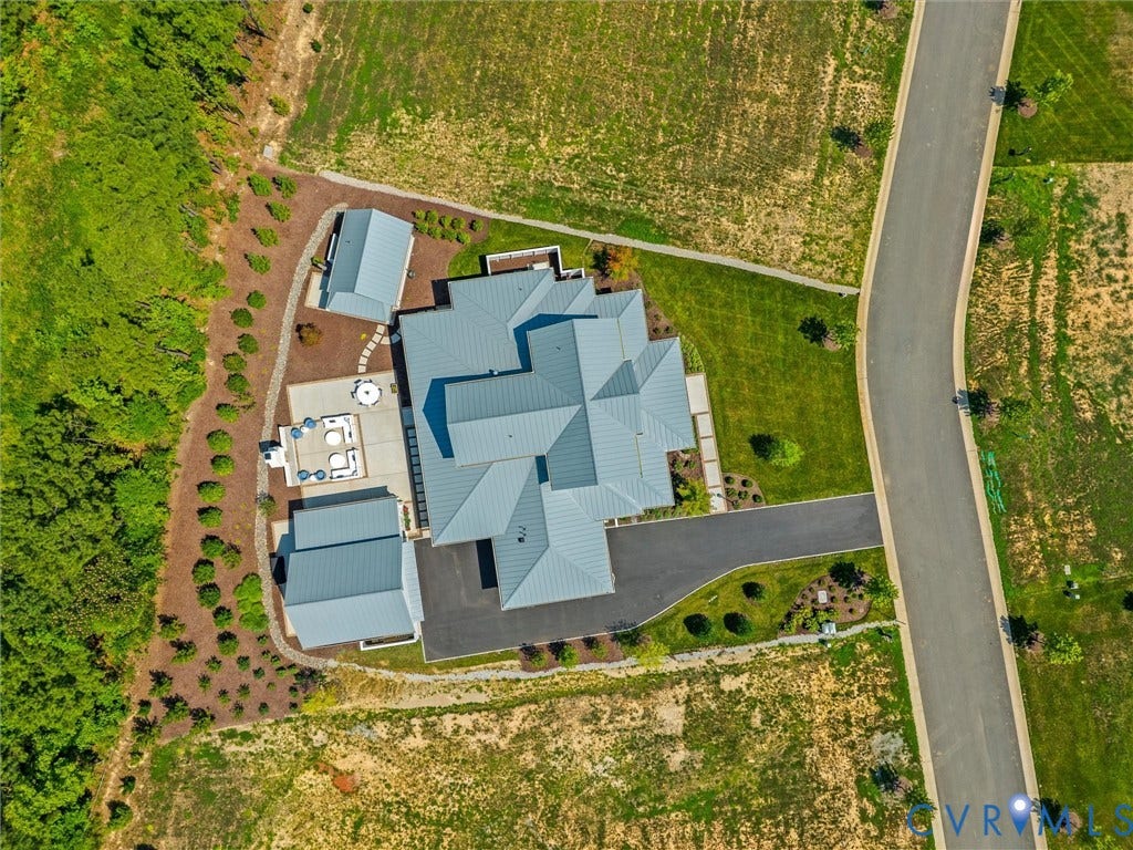 Contemporary home featuring a multi-gabled roofline, expansive paved driveway, and detached ancillary structures