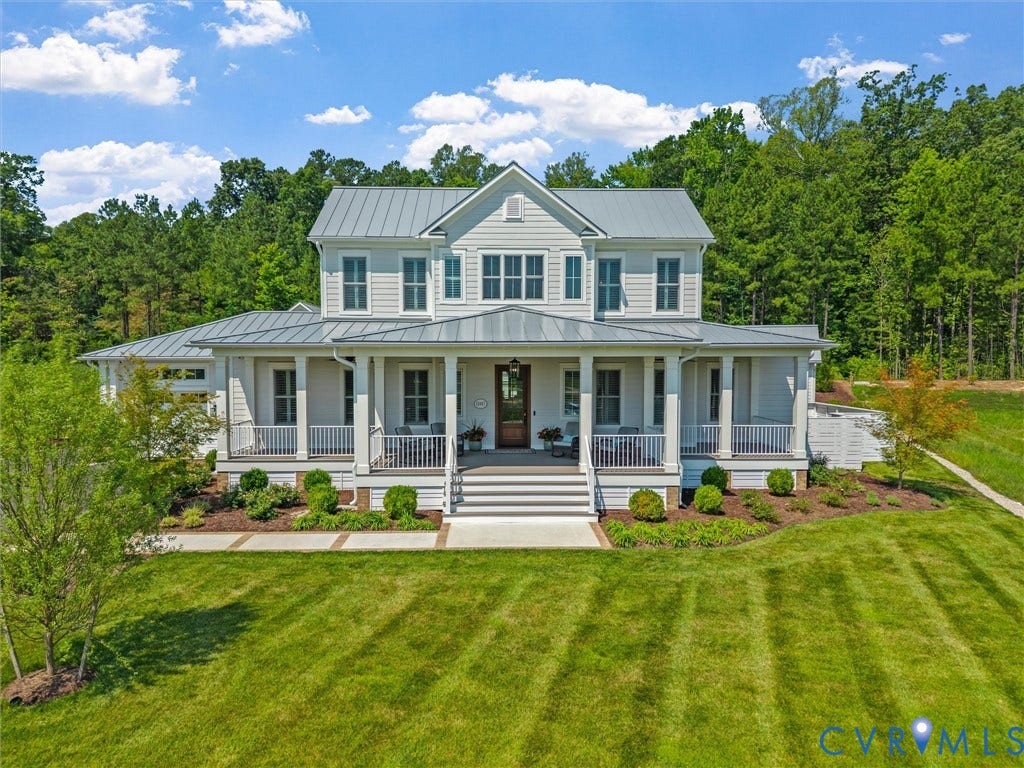 Two-story residence featuring light gray siding, a prominent front porch with white railings, and a multi-gabled metal roof