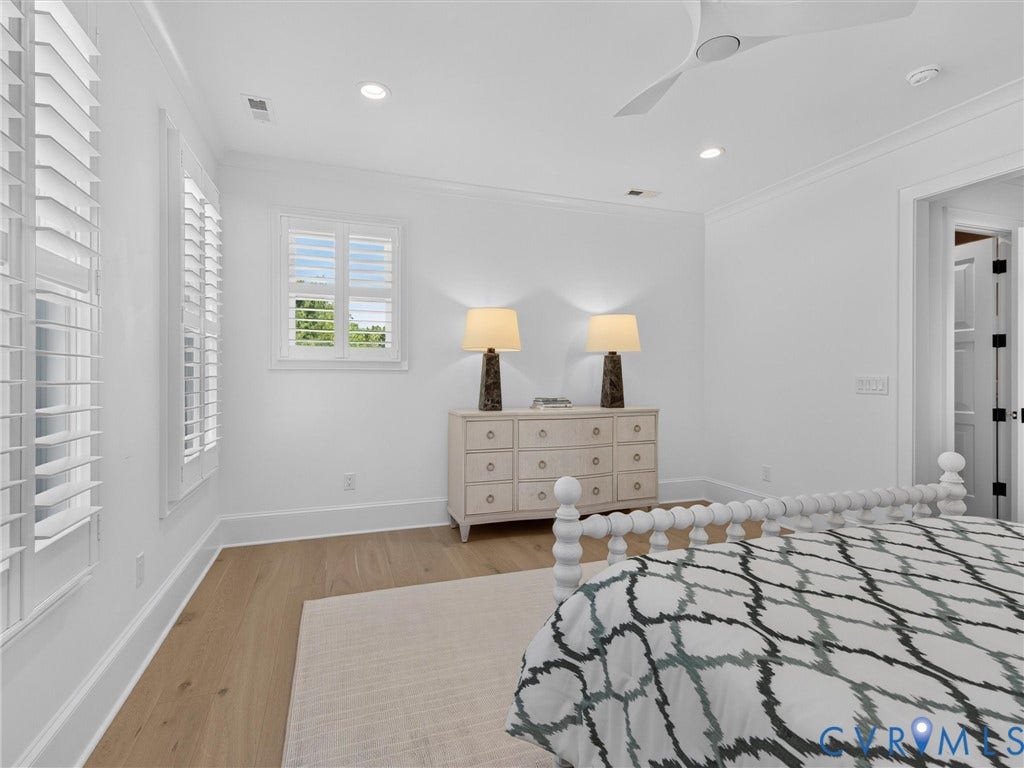 Interior room featuring light wood-finish flooring, white walls, and a white ceiling with a modern ceiling fan