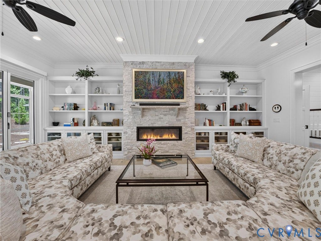 Living space with a stone-clad fireplace and linear firebox, flanked by built-in shelving and cabinetry