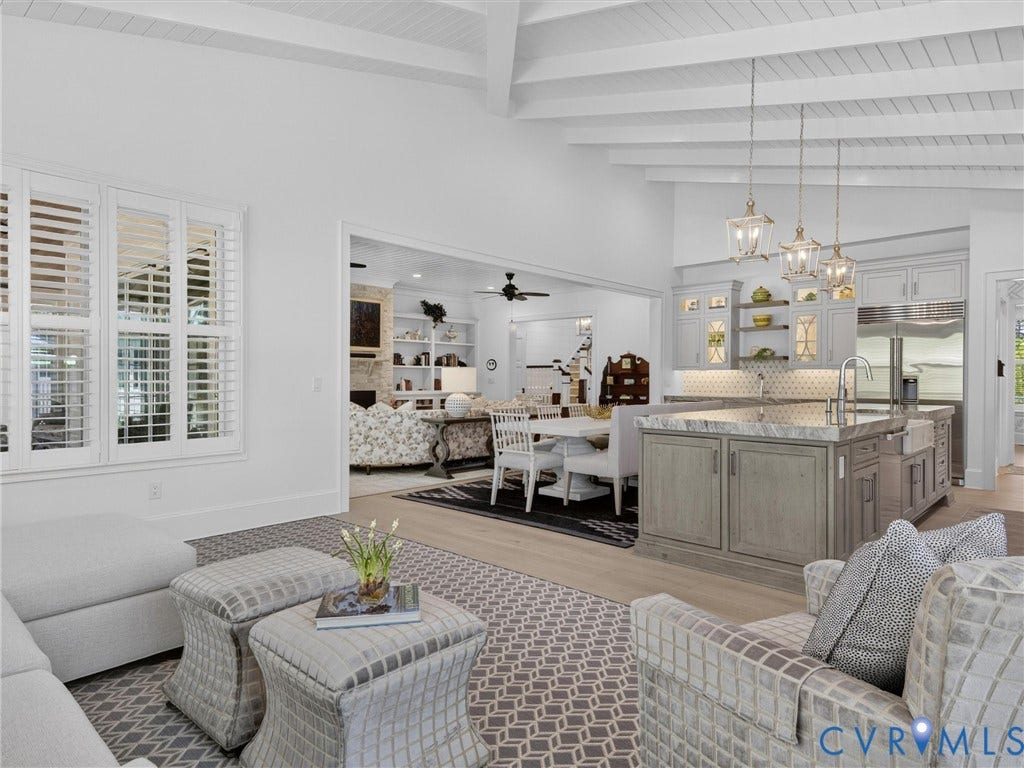 Vaulted ceiling with exposed beams, light wood-finish flooring, and a kitchen island with seating