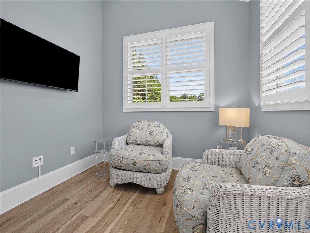 Light blue painted walls with crisp white trim, wood-finish flooring, and white plantation shutters