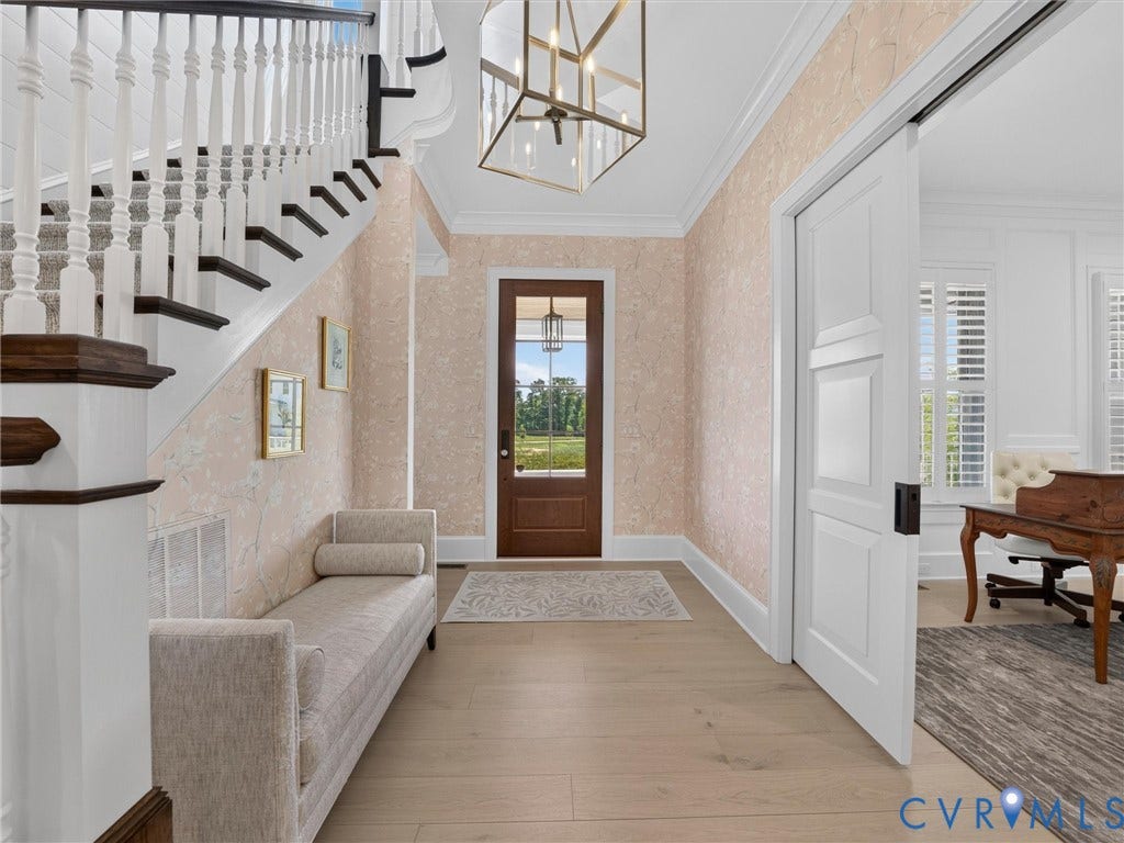 Foyer showcasing a wooden front door with glass paneling, a grand staircase with dark wood handrails and white balusters, and light wood-finish flooring