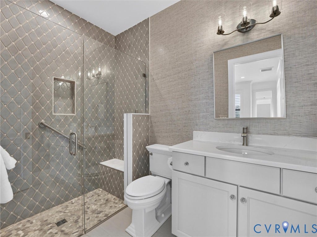 Walk-in shower with diamond-patterned tile, integrated niche, and glass enclosure