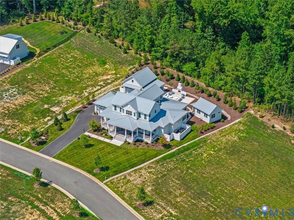 Expansive residential property featuring a multi-gable main residence with a metal roof and full-length covered porch