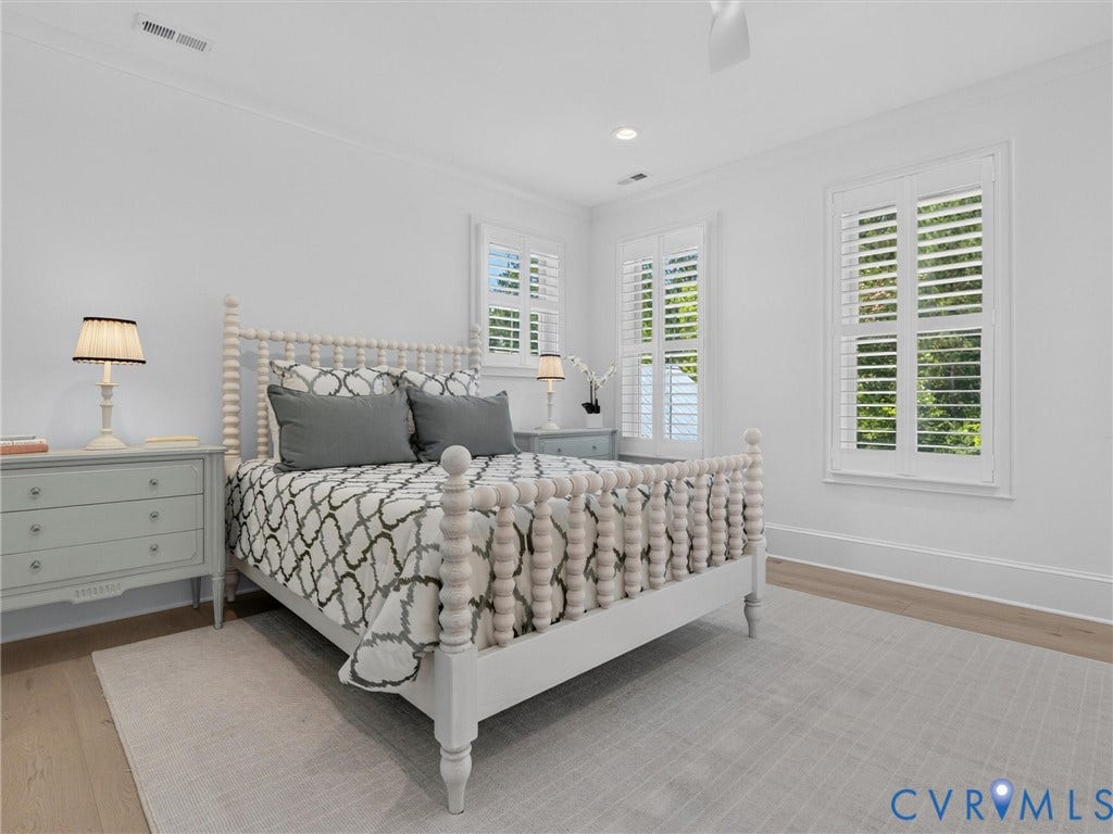 Bright bedroom featuring light wood-finish flooring and white walls with crown molding
