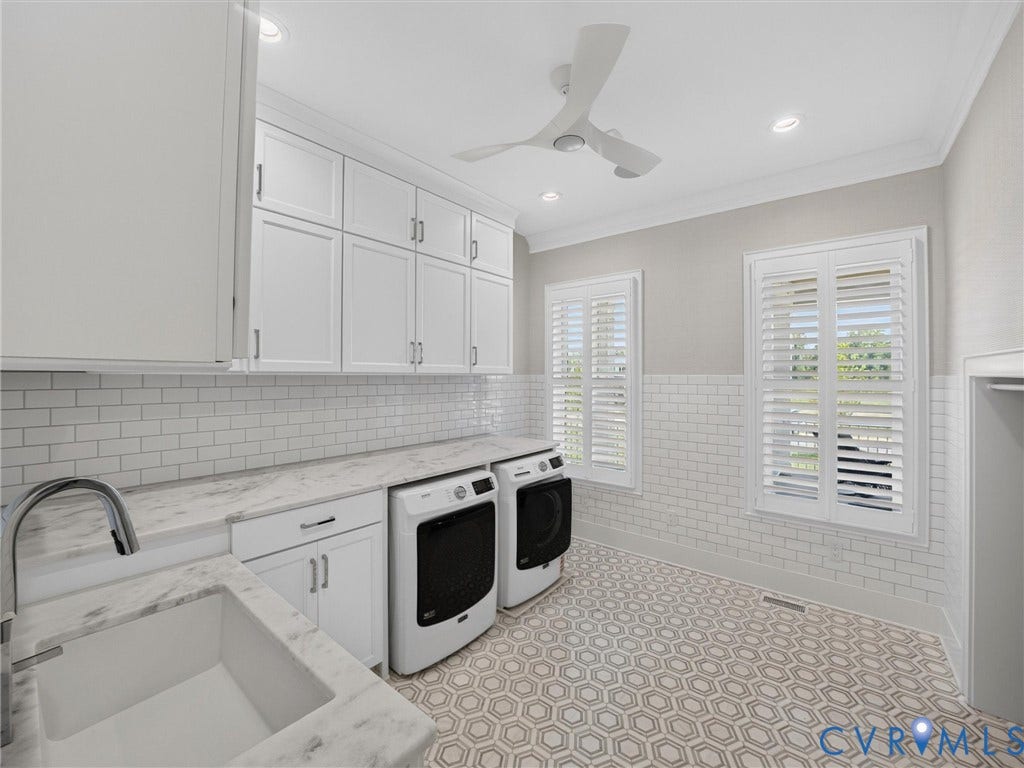 Spacious utility room featuring extensive white cabinetry, marble-finish countertops, a white subway tile backsplash, and hexagonal floor tiling