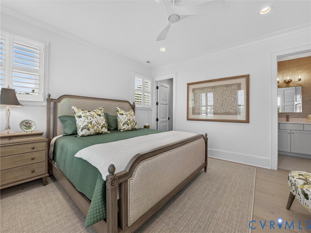 Bedroom featuring light wood-finish flooring, two large windows with plantation shutters, crown molding, and a ceiling fan with integrated lighting