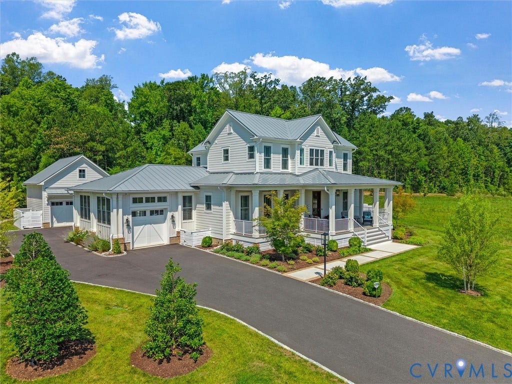 Classic light gray siding exterior with a wraparound porch, featuring a metal roof and white trim