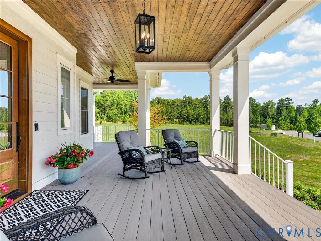 Spacious front porch featuring a wood-finish ceiling, durable composite decking, white columns, and a coordinating railing system