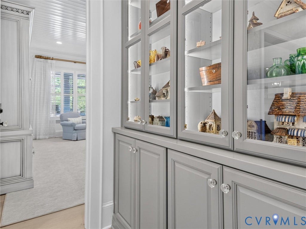 Built-in cabinetry featuring glass-front display cabinets with interior lighting, lower storage, and clear knob hardware