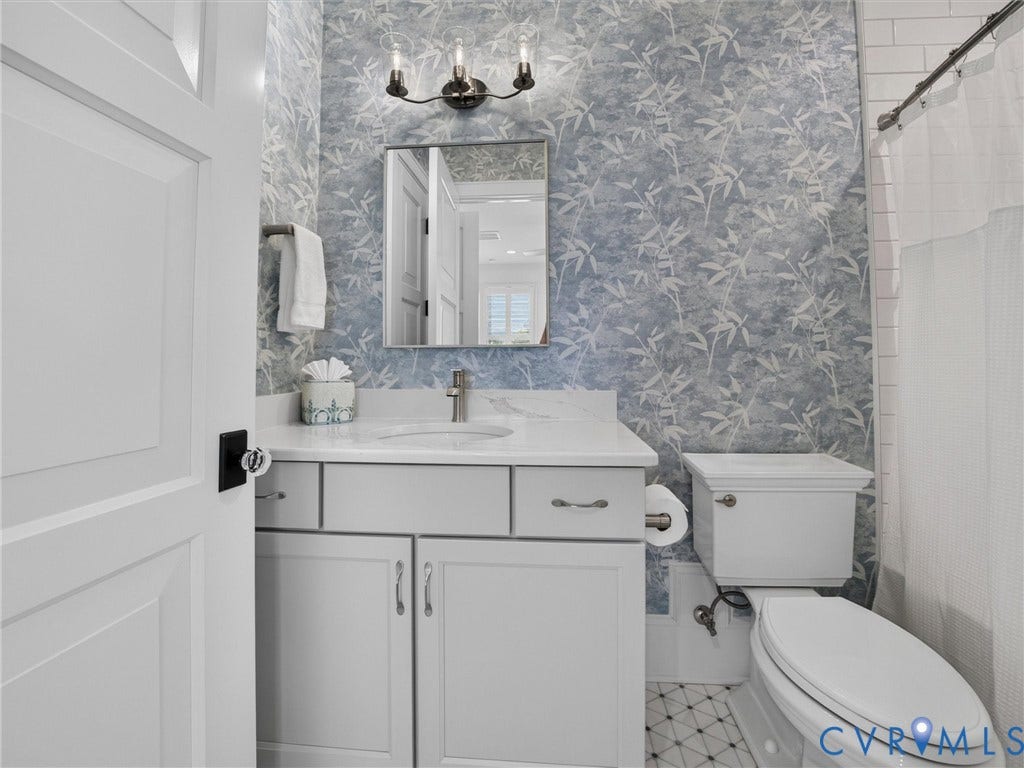Bathroom featuring a white vanity with a light countertop, an undermount sink, and a wall-mounted mirror