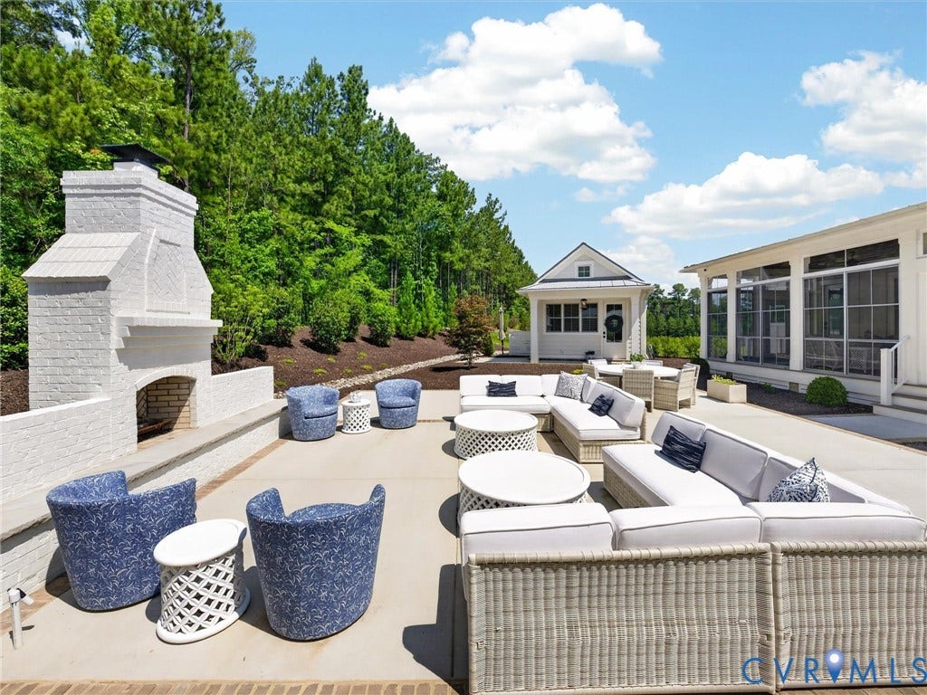 Spacious outdoor patio featuring a white brick fireplace, a separate screened porch structure, and an additional detached structure