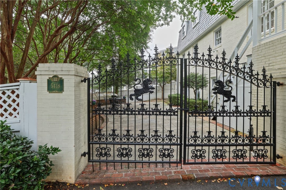 5418 Cary Street Road, Richmond, VA 23226 Gated entrance featuring ornate wrought-iron double doors, brick-bordered stone paved courtyard, and painted brick exterior walls