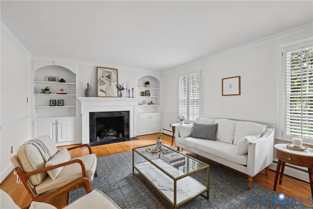 5418 Cary Street Road, Richmond, VA 23226 Living area featuring wood-finish flooring, a wood-burning fireplace with stone surround, custom built-in cabinetry, and white plantation shutters