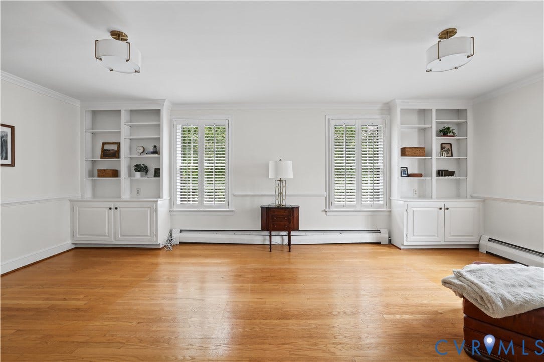 5418 Cary Street Road, Richmond, VA 23226 Wood-finish flooring, dual built-in floor-to-ceiling bookshelves with cabinetry, windows featuring white plantation shutters, and dual semi-flush mount drum light fixtures