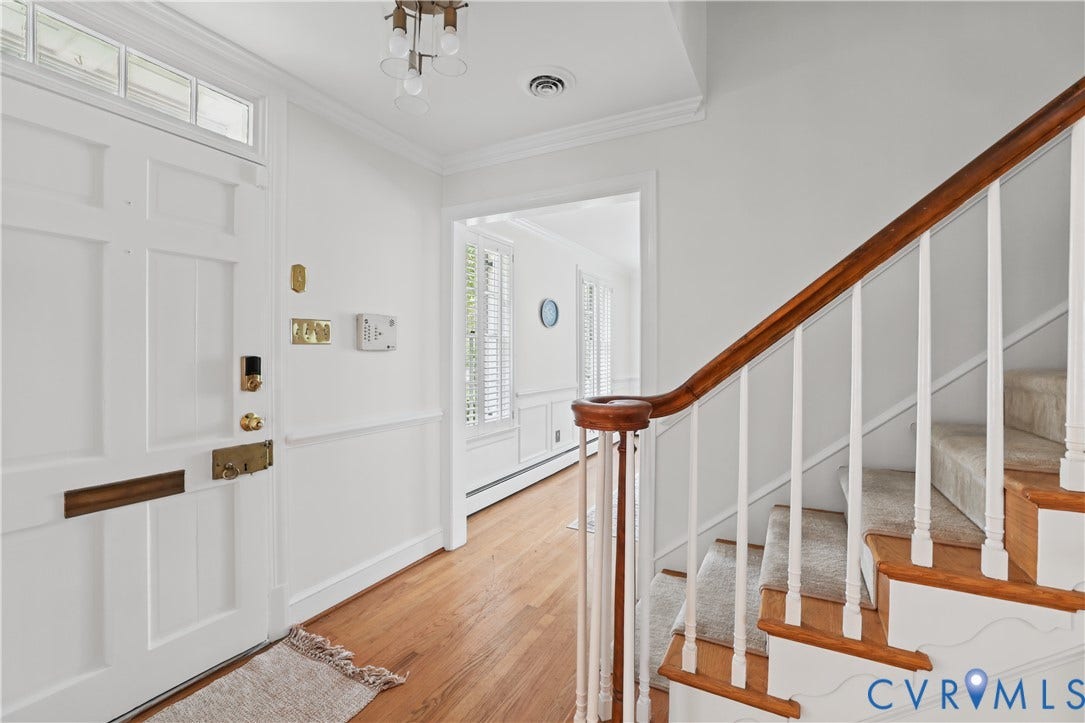 5418 Cary Street Road, Richmond, VA 23226 Foyer featuring a paneled front door with transom window, wood-finish flooring, wainscoting, and a staircase with a wooden handrail and white balusters