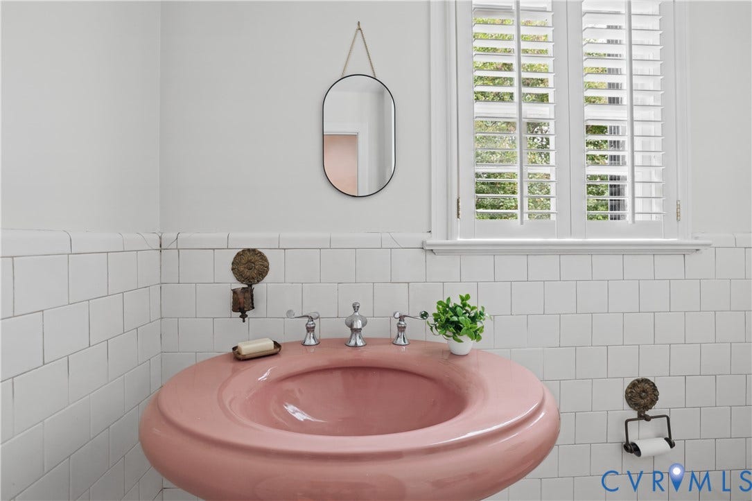 5418 Cary Street Road, Richmond, VA 23226 Wall-mounted ceramic pedestal sink in a curved silhouette, white square tile wainscoting, and window with white plantation shutters