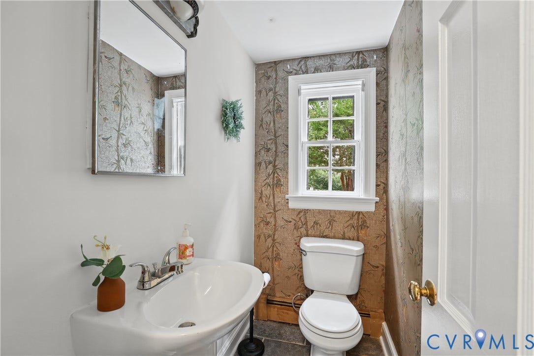 5418 Cary Street Road, Richmond, VA 23226 Powder room featuring patterned wallpaper, a wall-mounted sink with a chrome faucet, a rectangular framed mirror, a multi-pane window, and a standard-height toilet