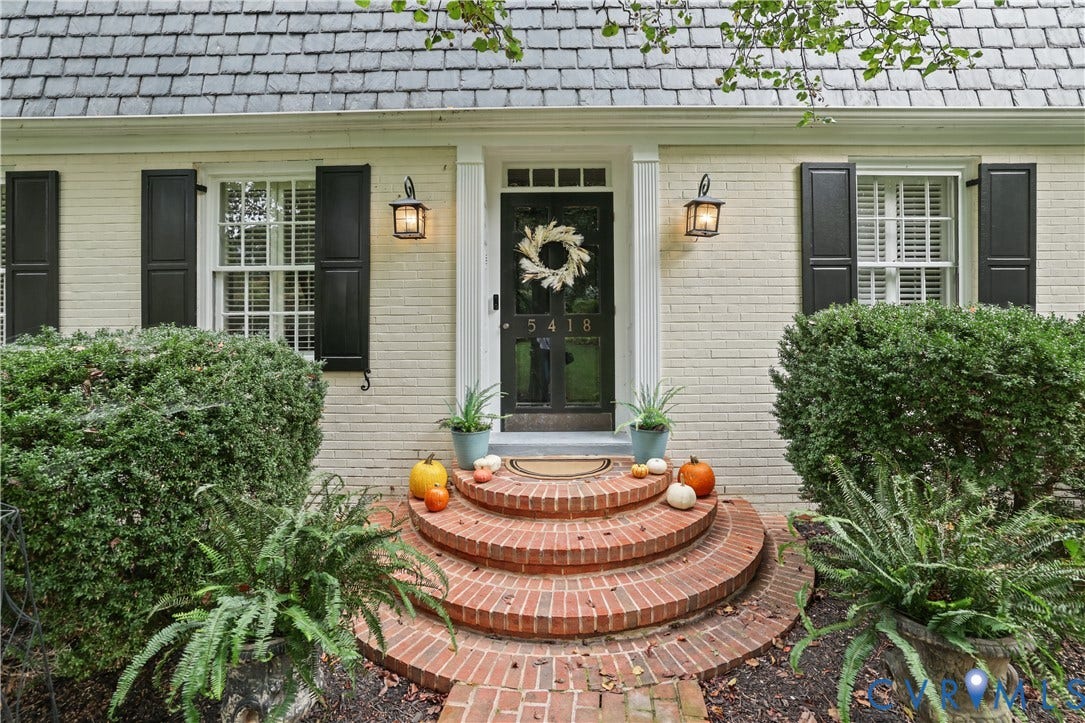 5418 Cary Street Road, Richmond, VA 23226 Brick exterior with shuttered windows, slate-style roofing, and curved masonry front steps leading to a central glass-paneled door flanked by wall-mounted lanterns