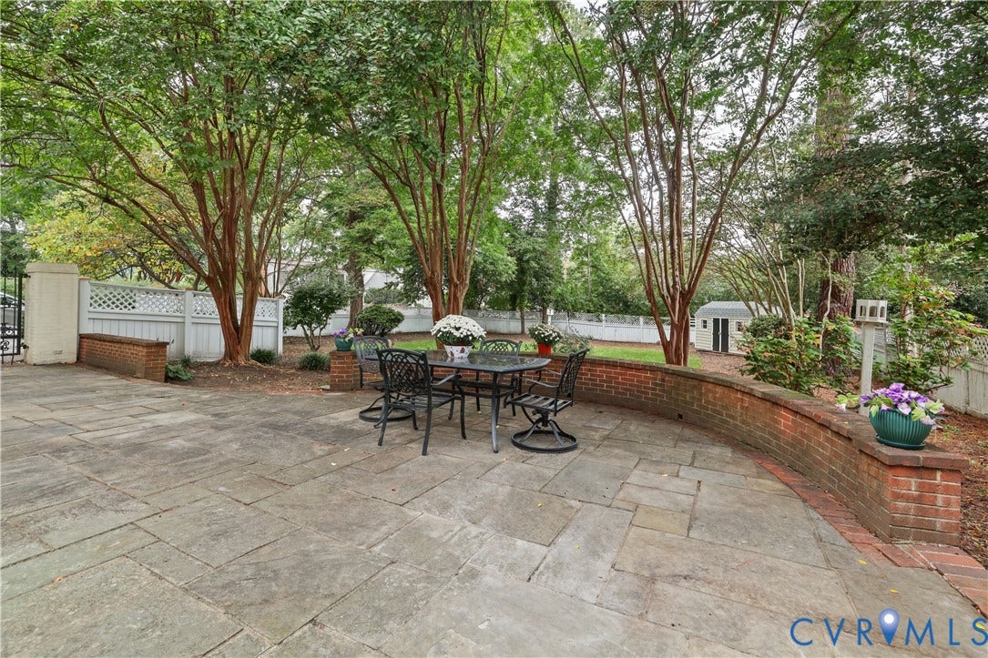 5418 Cary Street Road, Richmond, VA 23226 Flagstone patio featuring a curved brick retaining wall, white lattice fencing, and mature trees