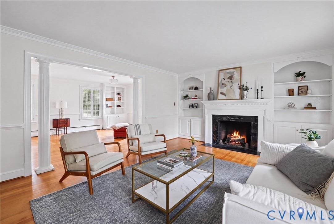 5418 Cary Street Road, Richmond, VA 23226 Living area featuring wood-finish flooring, a fireplace with a dark stone surround and white mantel, symmetrical built-in shelving, and architectural columns