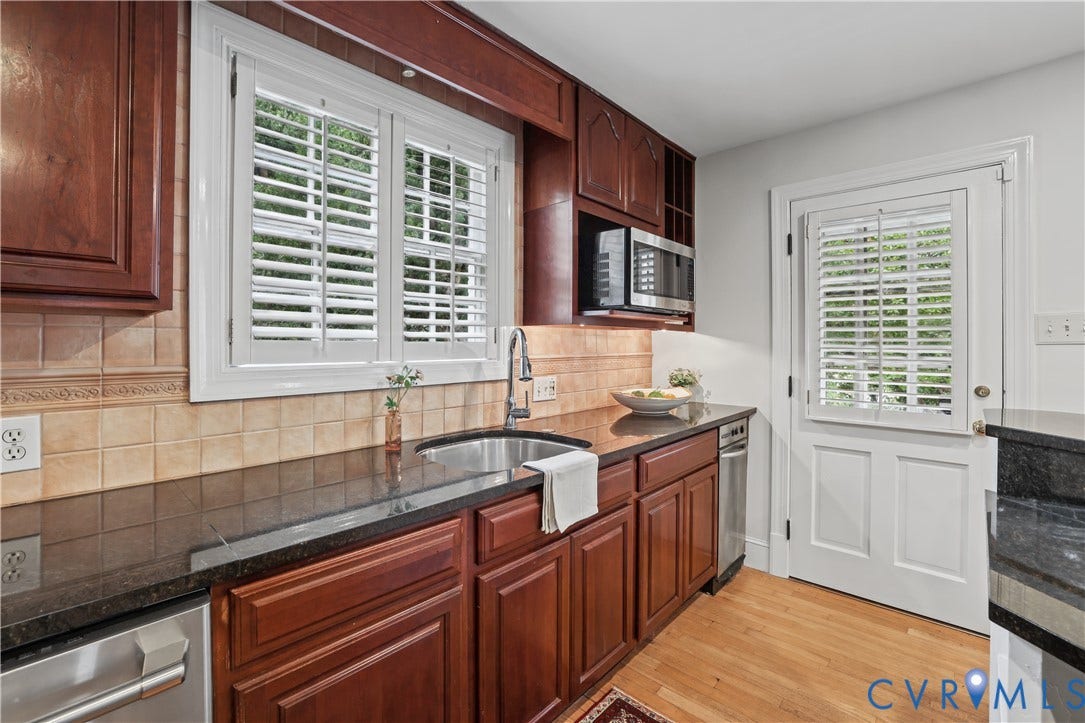 5418 Cary Street Road, Richmond, VA 23226 Stained wood cabinetry, stone countertops, tiled backsplash, stainless steel sink with gooseneck faucet, and wood-finish flooring