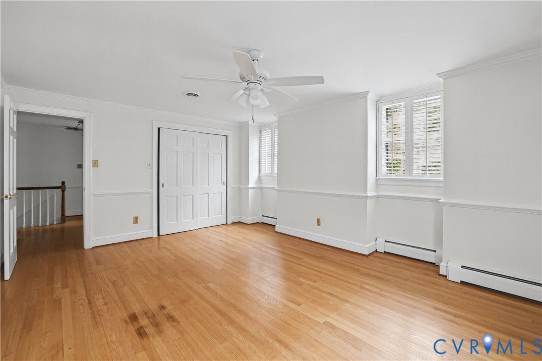 5418 Cary Street Road, Richmond, VA 23226 Interior room featuring wood-finish flooring, chair rail molding, a white ceiling fan with integrated lighting, dual-pane windows with plantation shutters, and a sliding door closet