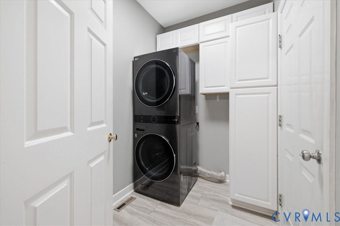 The laundry room offers cabinetry and the stackable washer and dryer stay with the home!