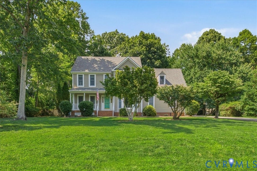 Traditional two-story residence with light-colored siding and a covered front porch featuring white columns