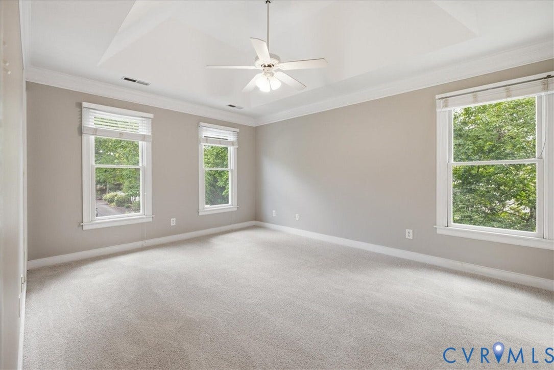 The primary bedroom offers a tray ceiling, crown molding, a ceiling fan and NEW carpet!