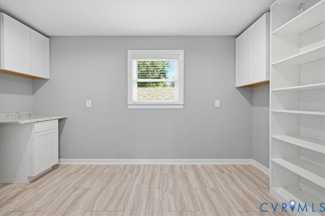 Versatile room featuring wood-finish flooring, a window with horizontal blinds, built-in open shelving, and a built-in counter with upper and lower cabinetry