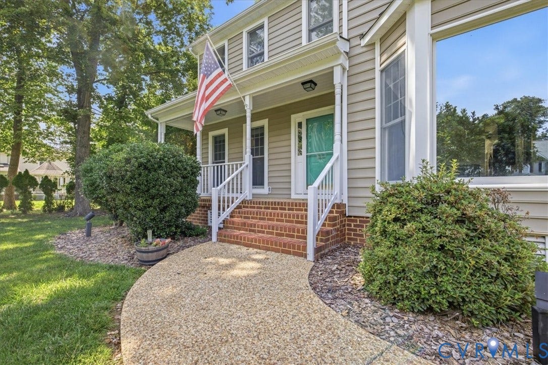 Front porch entry featuring a teal door, white railings, and brick stairs