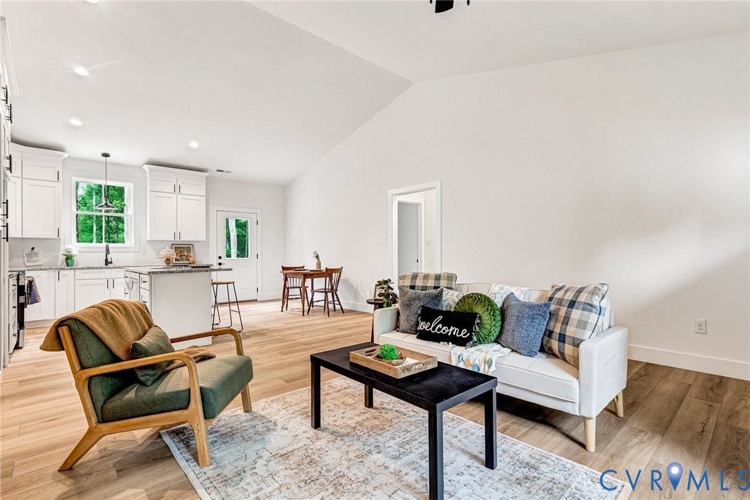 716 Pine Harbour Drive, Pine Harbour, Mineral, VA 23117 Open-concept living area featuring vaulted ceilings, wood-finish flooring, a kitchen with white cabinetry and dark hardware, a center island with countertop seating, and recessed lighting