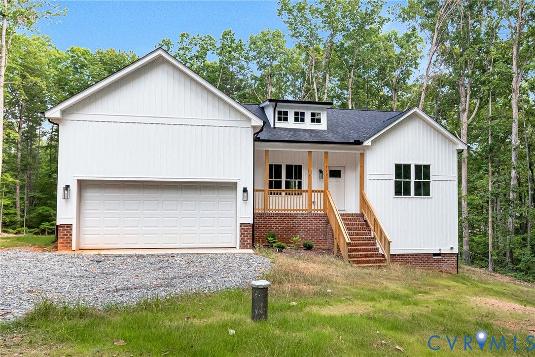 716 Pine Harbour Drive, Pine Harbour, Mineral, VA 23117 Modern farmhouse-style exterior featuring white vertical siding, a dark shingle roof, a prominent front porch with natural wood accents, a brick foundation, and a gravel driveway