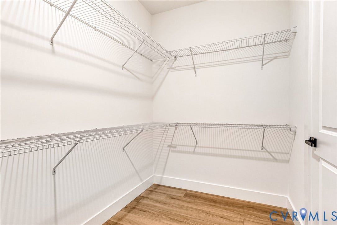 716 Pine Harbour Drive, Pine Harbour, Mineral, VA 23117 Walk-in closet featuring wire shelving, wood-finish flooring, white baseboards, and a white panel door with matte black hardware