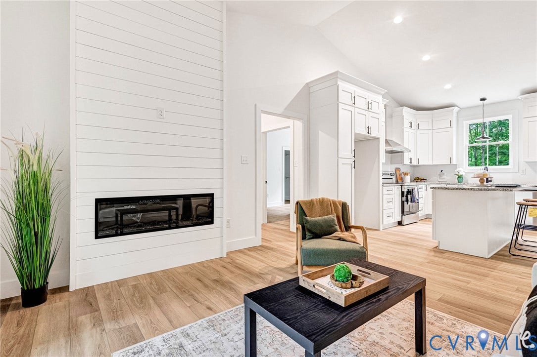 716 Pine Harbour Drive, Pine Harbour, Mineral, VA 23117 Open-concept living space featuring wood-finish flooring, a contemporary linear fireplace with shiplap surround, and a vaulted ceiling