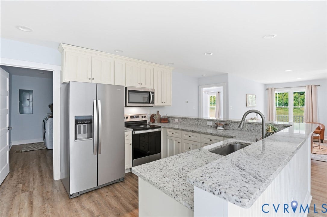2677 Dogtown Road, Goochland, VA 23063 Bright kitchen featuring white cabinetry, stainless steel appliances, speckled stone countertops, a stainless steel undermount sink with a high-arc faucet, and wood-finish flooring