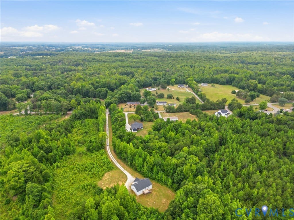 2677 Dogtown Road, Goochland, VA 23063 Expansive wooded acreage with a long, private driveway leading to a single-story residence featuring a dark gray roof